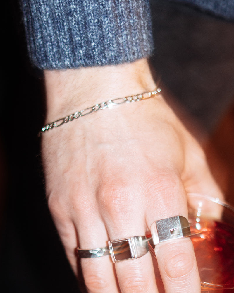 Figaro Bracelet 5mm - styled with Crown Signet Ring, Onyx Signet Ring and Hammered Band Ring, Figaro chain bracelet on wrist, hand holding cocktail
