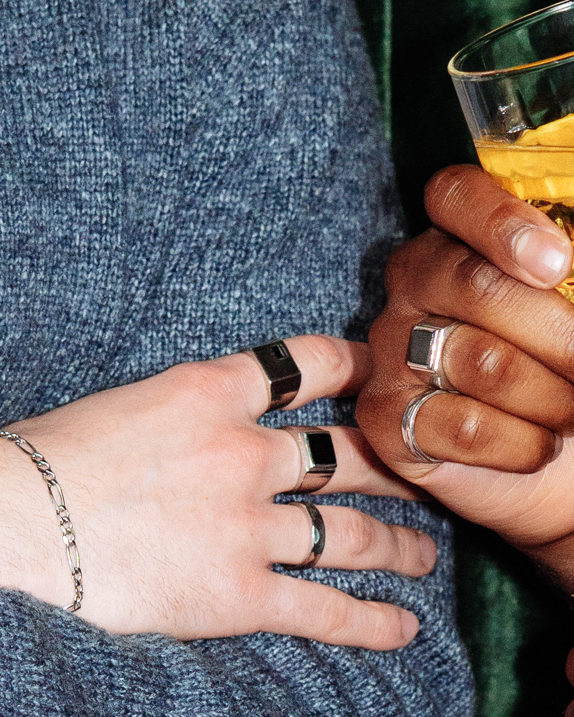 Onyx Signet Ring - stacked with Crown Signet Ring and Hammered Band Ring, two hands close-up holding cocktail glasses