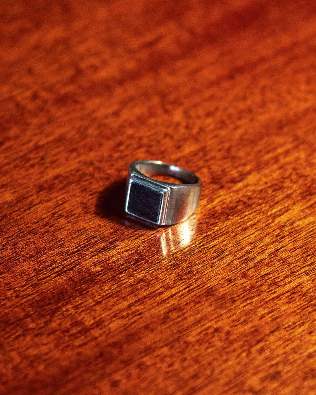 Onyx Signet Ring - single ring on dark wood surface in low light