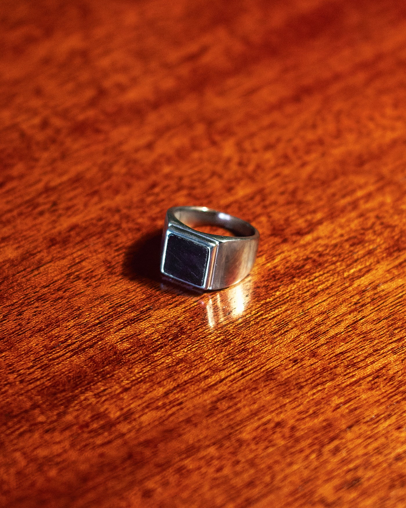 Onyx Signet Ring - single ring on dark wood surface in low light