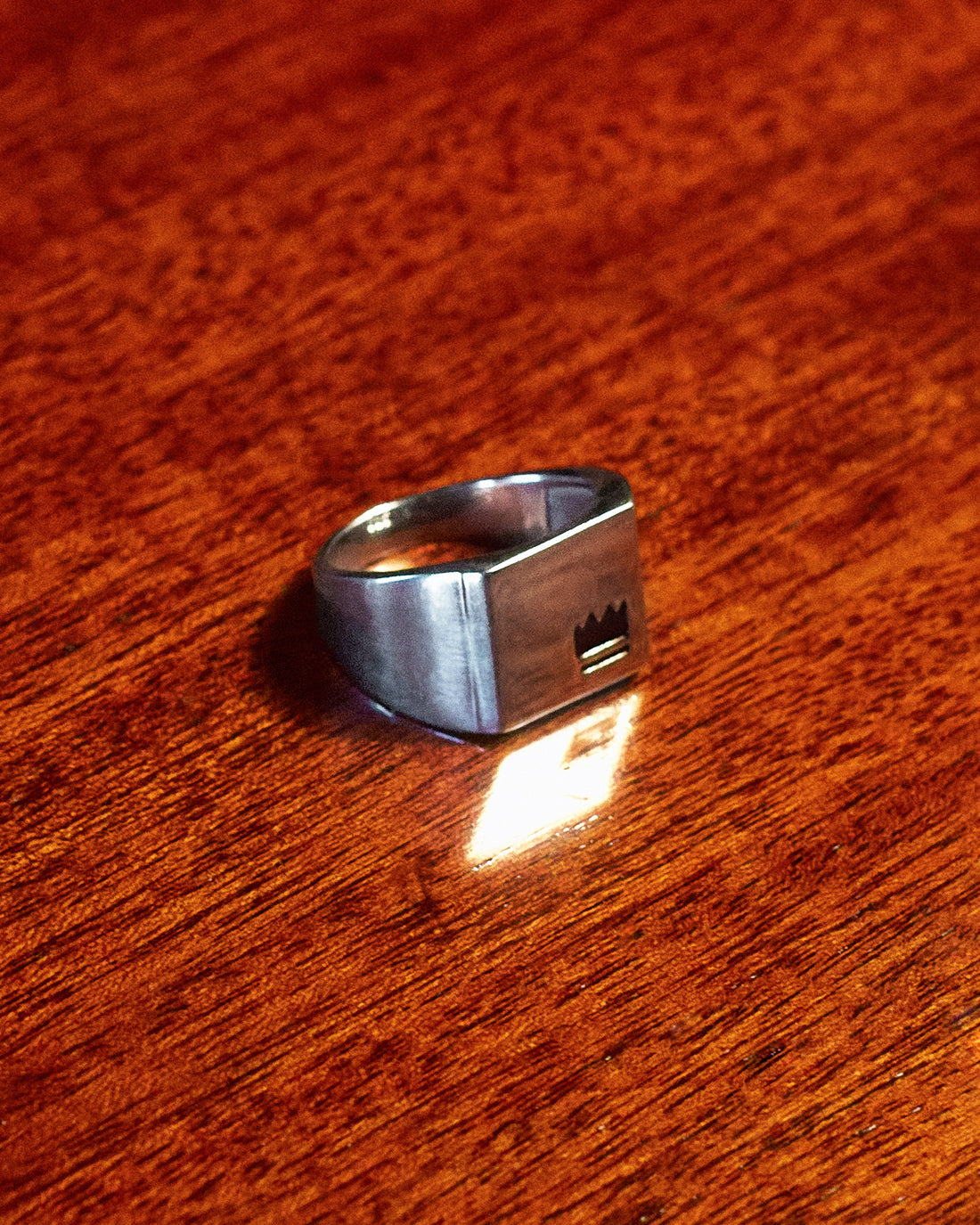 Crown Signet Ring - single ring on dark wood surface in low light