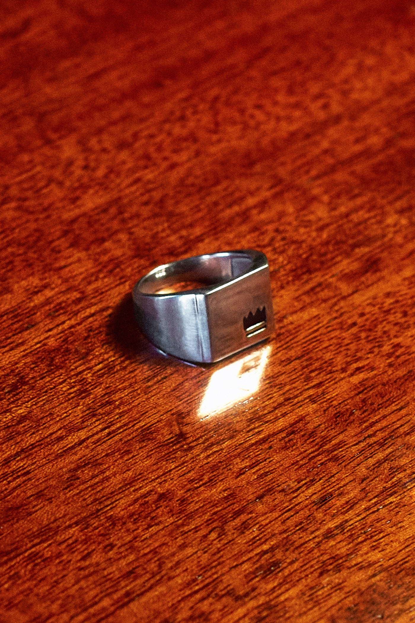Crown Signet Ring - single ring on dark wood surface in low light
