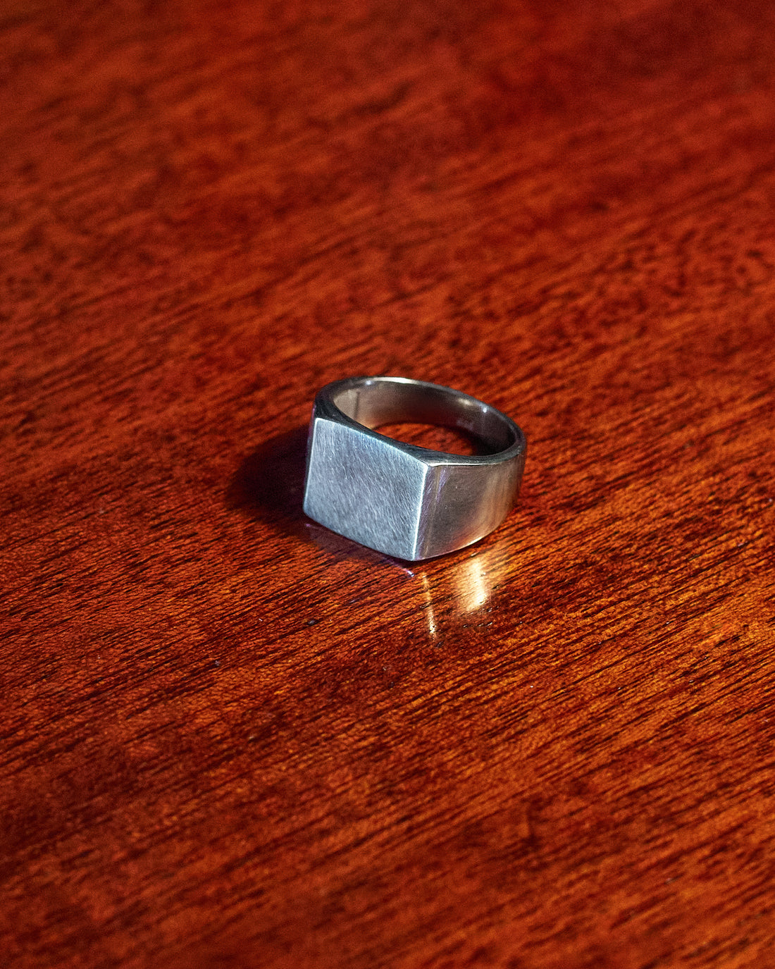 Plain Signet Ring - single ring on dark wood surface in low light