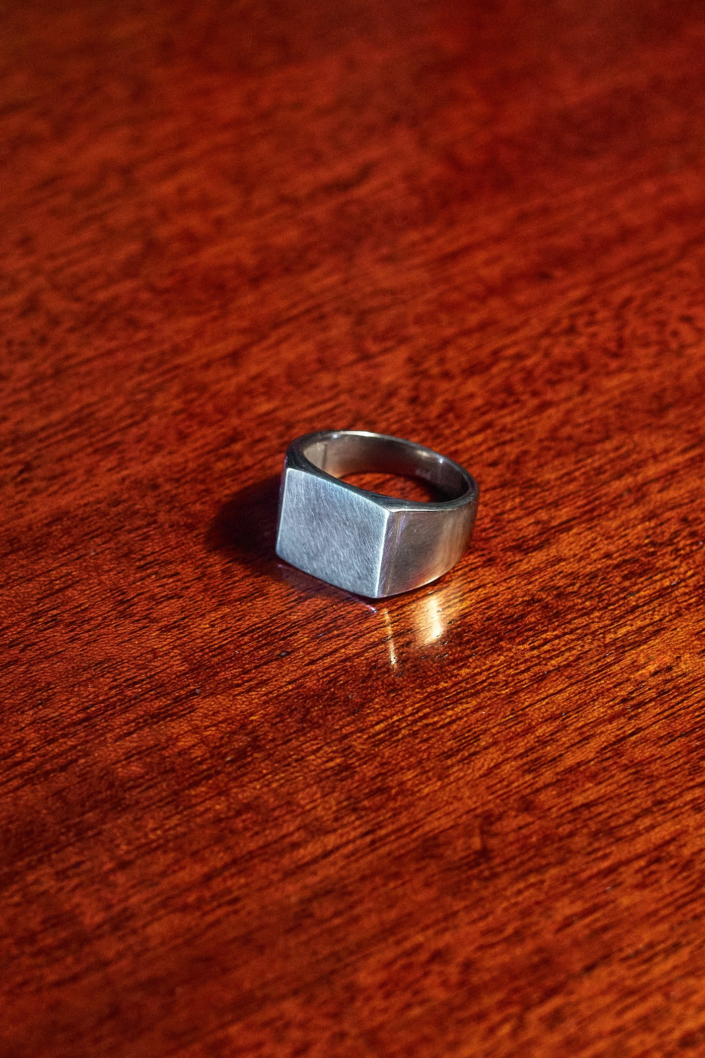 Plain Signet Ring - single ring on dark wood surface in low light