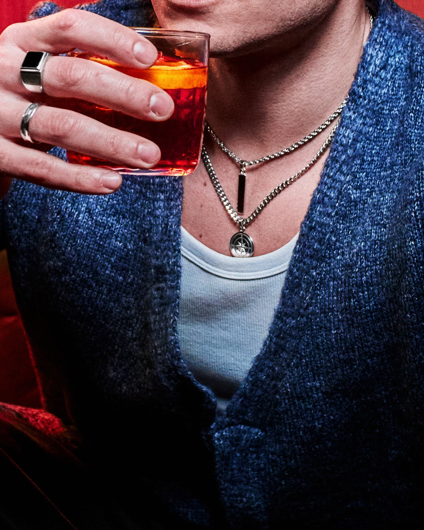 Compass Pendant - styled with Onyx Signet Ring and Hammered Band Ring, Figaro chain bracelet on wrist, model in blue cardigan holding negroni