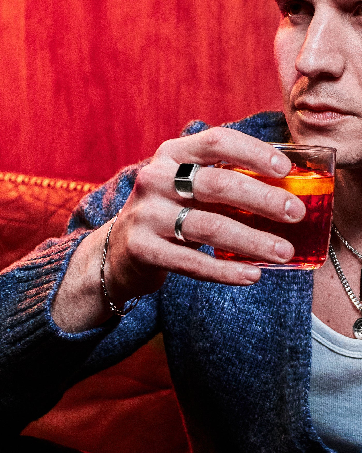 Hammered Band Ring - styled with Onyx Signet Ring and Compass Pendant, Figaro chain bracelet on wrist, model in blue cardigan holding negroni