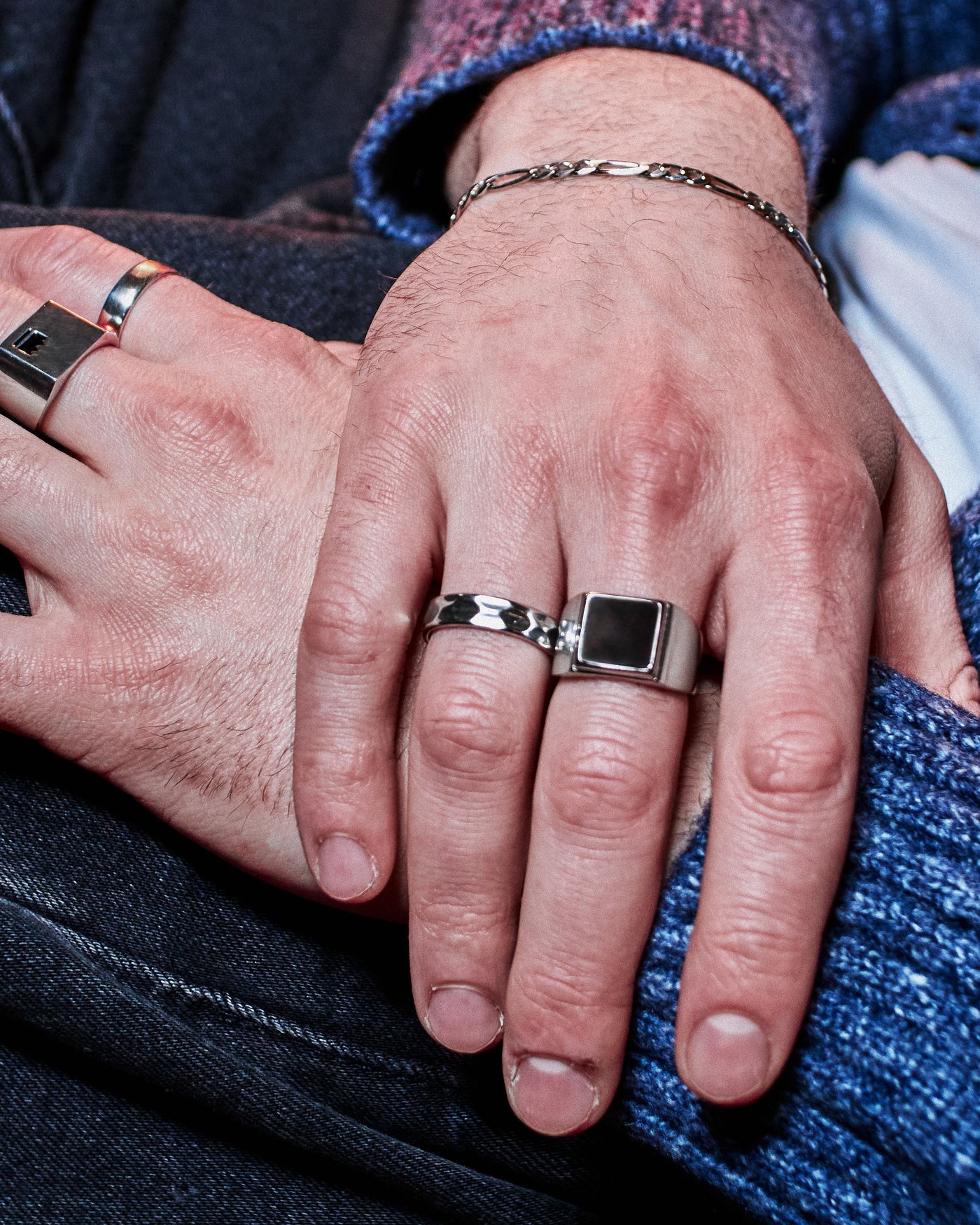 Hammered Band Ring - stacked with Crown Signet Ring and Plain Band Ring, hand resting on dark denim jacket