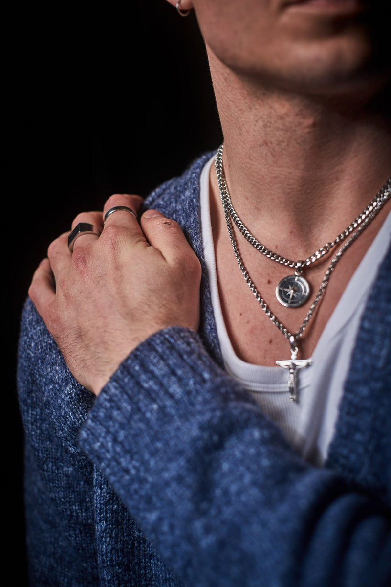 Cuban Chain 5mm - Hand on shoulder with layered silver necklaces and rings, blue cardigan.