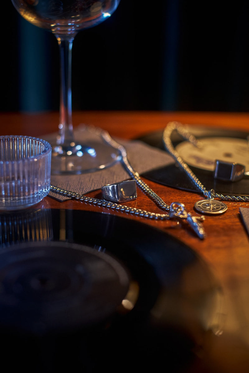 Byzantine Chain 5mm - Masculine jewelry, sophisticated setting with glass and records, creating a moody ambiance.