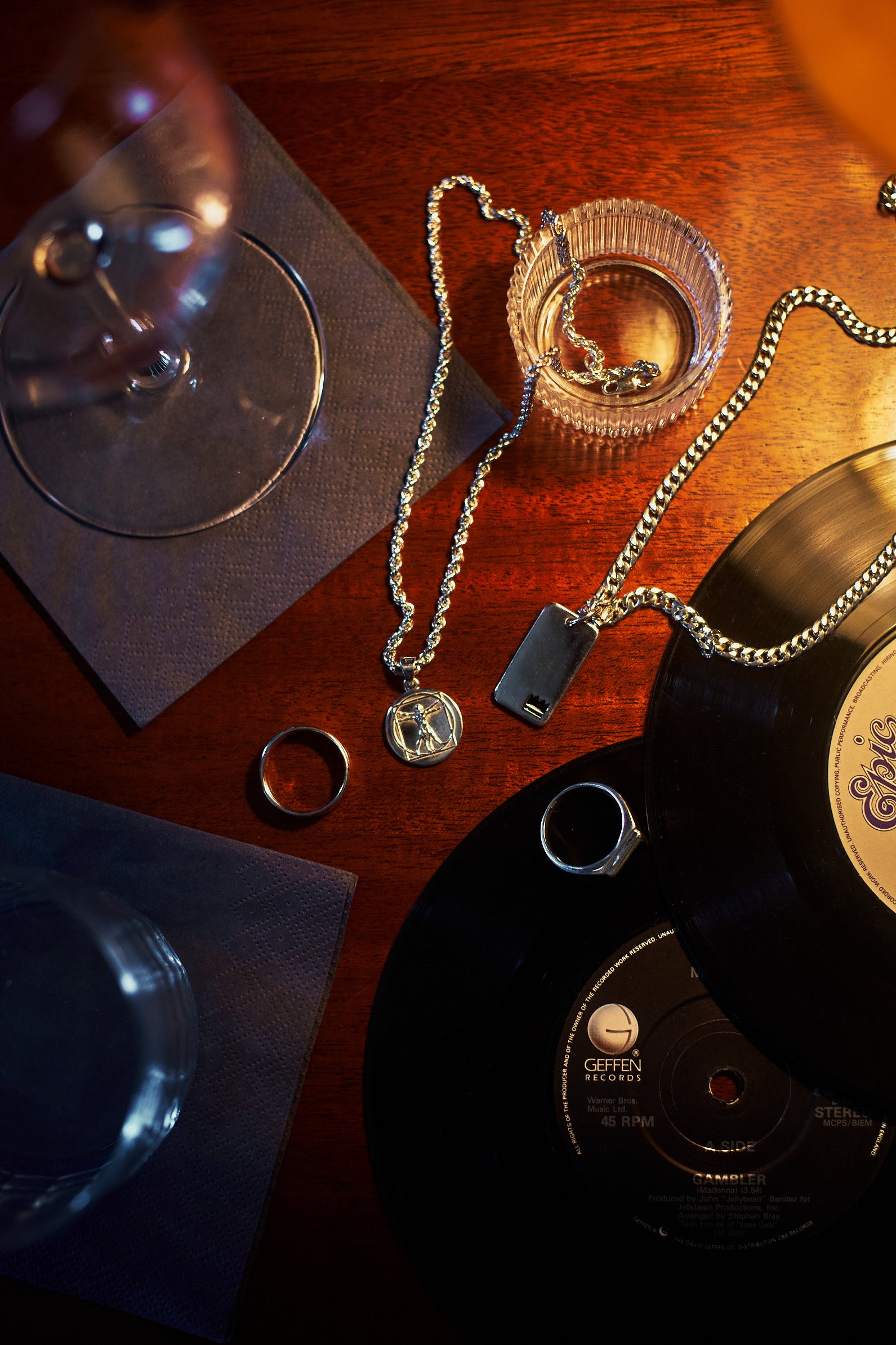Moody flatlay - rings pendants vinyl records drinks on wooden table